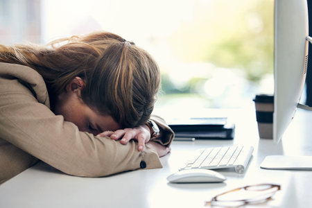 Tired business woman, sleeping and desk in burnout, stress or mental breakdown at office. Exhausted female person or employee resting head on table in depression, anxiety or overworked at workplaceの写真素材