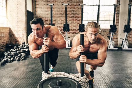 Men, weights training and together with sled, rope and top view for fitness, health or workout with pushing. Bodybuilder partnership, friends and teamwork for exercise, coaching or muscle developmentの写真素材
