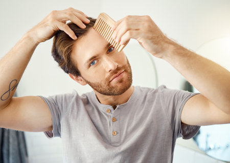 Bathroom portrait, brush and man with hair maintenance, texture grooming or morning self care. Salon, wellness and person with comb for healthy hairstyle growth, styling treatment or home hygieneの写真素材