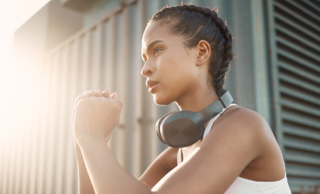 Fitness, woman with headphones and training with lens flare in the morning. Workout or exercise, warm up in sportswear or healthy lifestyle and female athlete squat for cardio health wellnessの写真素材