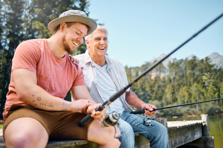 Happy man, father and fishing in lake for fun bonding, hobby or relaxing together in the nature outdoors. Elderly male person laughing with son and enjoying time to catch fish on holiday by forestの写真素材