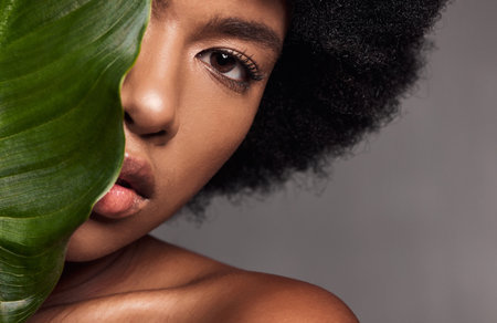 Black woman, eye and leaf, natural beauty and eco friendly cosmetics with facial on studio background. Face, portrait and African model with lashes, skincare and glow with sustainable dermatologyの写真素材