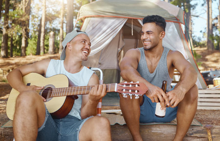 Men, friends and guitar for camping in woods with smile, singing and beer for drink, relax and holiday. Young male students, musician and happy people with instrument, creativity and art in forrestの写真素材