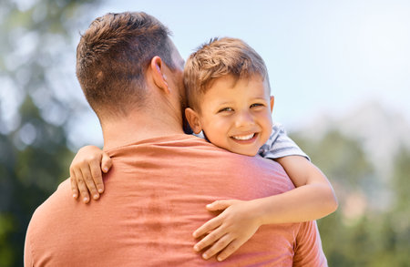 Portrait, father and son hug, outdoor and smile with quality time, bonding and loving together. Face, dad and male child with happiness, kid and parent embrace, park and care with joy and supportの写真素材