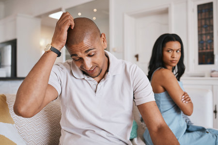 Couple, fight and stress on living room sofa for worry, mistake or angry with problem in house. Man, woman or depression for conflict, drama or frustrated on lounge couch for cheating, crisis or failの写真素材
