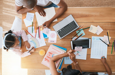 Top view, home and girl with parents, homework and learning with support, care and bonding at desk. Father, mother and daughter with drawing, education and teaching with technology in family houseの写真素材