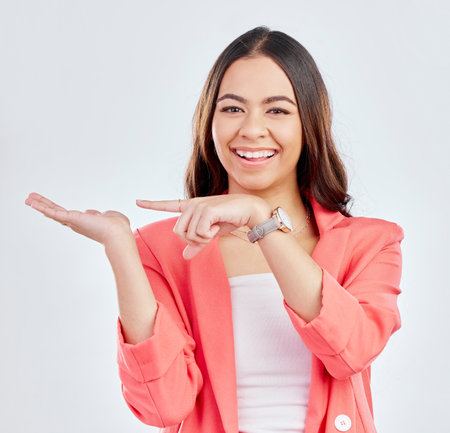 Pointing, portrait or hand of happy woman for a sale, retail product offer or discount deal in studio. Option, smile or girl showing mockup space or menu choice promotion isolated on white backgroundの写真素材