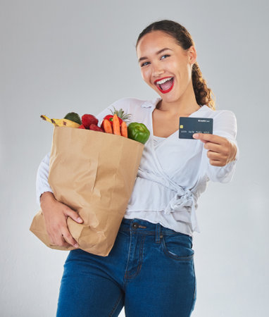Credit card, portrait and woman grocery shopping online for fruits in studio isolated on a white background. Sustainable bag, food and excited customer with digital money, ecommerce and fintech salesの写真素材