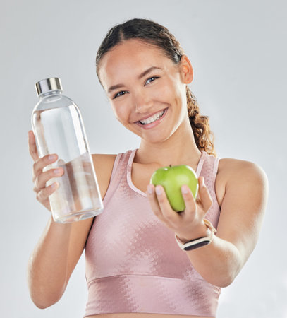 Portrait, woman and fitness with apple, water and in studio for diet of healthy food, nutrition and...