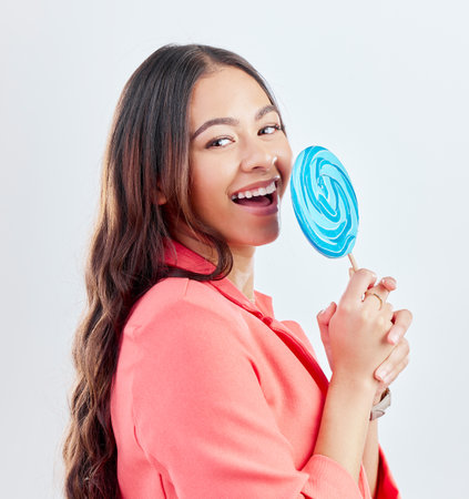 Portrait, lollipop and woman with sweets, funny and happiness against a white studio background. Face, female person or happy model with candy, dessert and laughing with a smile, humor and creativityの写真素材