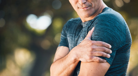 Arm pain, outdoor and man in a park with sport injury and muscle strain from fitness and workout. Exercise problem, male person and back with medical, health and problem from training accidentの写真素材
