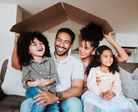 Sofa, parents and kids with cardboard roof and happy family together in living room of new home. Property, happiness and mom, dad and children on couch, mortgage and insurance with future security.の写真素材