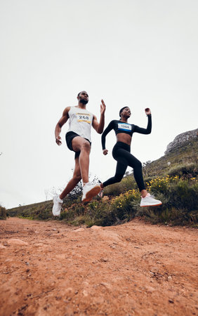 Running, jump and couple in mountain with fitness workout and training on a race and marathon. Runner, young people and road on a exercise challenge outdoor with sport cardio performance in natureの写真素材