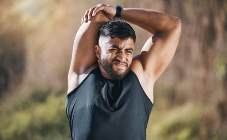 Fitness, stretching and man outdoor for training, running or workout on blurred background. Arm, stretch and Indian guy runner with body warm up in nature before exercise, run or cardio sport routineの写真素材