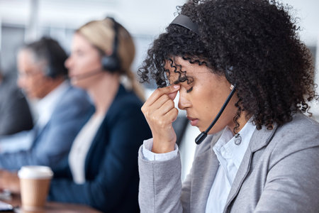 Headache, tired or woman in call center with burnout, head pain or overworked in crm communication. Migraine, office or stressed telemarketing sales agent frustrated with anxiety, fatigue or problemの写真素材
