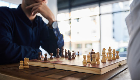 Board game, chess and men playing at a table in office while thinking of strategy or plan. Male friends together to play, relax and bond with wooden icon for problem solving, competition or checkmateの写真素材