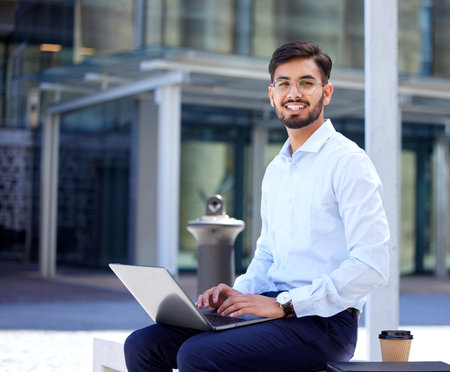 Portrait, business and man with a laptop, outdoor or typing with connection, digital software or network. Male person, employee or consultant with a pc, city or planning with a smile or data analysisの写真素材