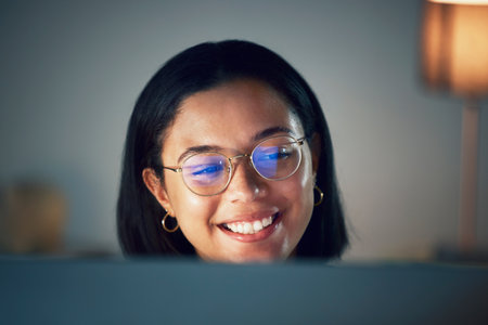 Glasses, laughing and woman streaming comedy show online, internet and at night in a home with subscription. Home, connection and young female person happy for watching on a pc with app serviceの写真素材