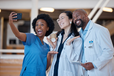 Diversity, happy and group selfie of doctors, surgeon or emergency care workforce in hospital, clinic or medical facility. Asian woman, black woman nurse and African man smile for healthcare photoの写真素材