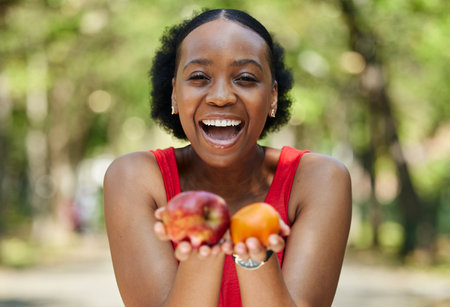 Apple, orange and portrait of a black woman with a fruit on a farm with fresh produce in summer and smile for wellness. Citrus, nutrition and young female person on an organic diet for self careの写真素材