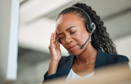 Call center stress, anxiety or black woman with headache pain due to burnout fatigue in a telecom office. Migraine, failure crisis or tired consultant depressed or frustrated by crm or sales deadlineの写真素材