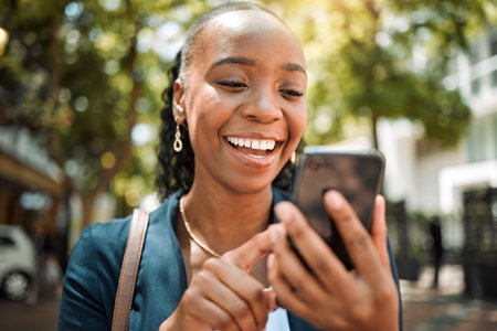 Outdoor, black woman and smartphone with a mobile app typing and happiness with social media, contact and email. Thinking, female person or girl with a cellphone, connection or website info in a cityの写真素材