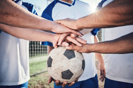 Football, hands together and collaboration for support, sports and training at stadium. Teamwork, group huddle and soccer players with motivation for exercise, workout goal and success in competitionの写真素材