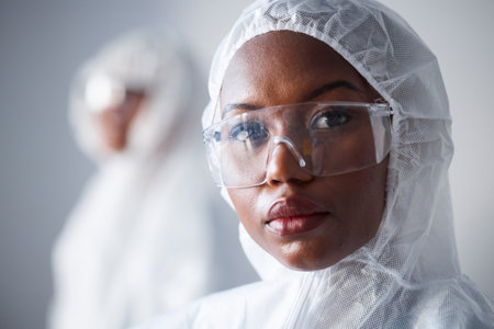 Science, serious and portrait of a black woman in a lab with a suit for security from virus. Face, hospital and an African scientist with glasses and clothes for safety from chemical and biotechの写真素材