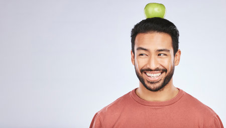 Head balance, thinking or happy man with apple decision for weight loss diet, healthy lifestyle change or nutrition choice. Studio food, fruit mockup space or hungry person ideas on white backgroundの写真素材