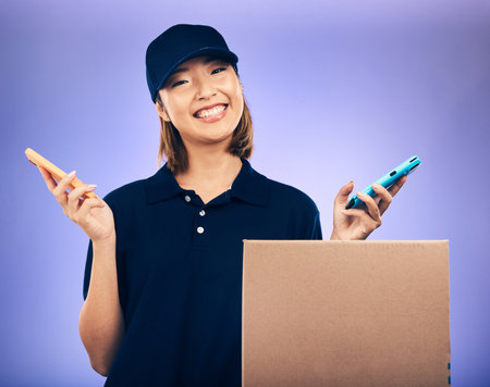 Courier, box and phone in studio portrait with smile, communication and e commerce by purple background. Happy Japanese woman, smartphone and package with delivery app, supply chain and logisticsの写真素材