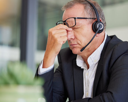 Call center, headache and business man stress, health problem or fatigue for communication or finance fail. Agent, consultant or sales person with eye pain, tired and online or financial mistakeの写真素材