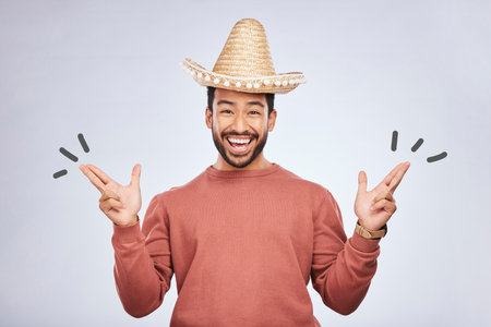 Finger gun, hat and portrait of man in studio with hand gesture for comic, humor and funny joke. Happy, Mexican party accessories and excited male person on gray background with sombrero for comedyの写真素材