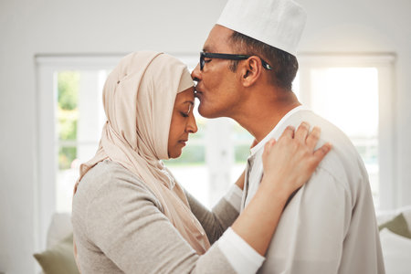 Home, Muslim elderly couple and forehead kiss, music slow dancing and bond for love, trust and care with kindness. Commitment, Islamic and Arab man, woman and senior people together for quality timeの写真素材