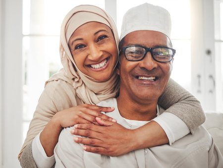 Portrait, Muslim and elderly couple smile, hug and happy for support, trust and care in retirement, bonding or marriage. Face, home and Islamic man, woman and elderly people together for quality timeの写真素材