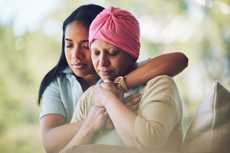 Love, sweet and woman with her mom with cancer hugging, bonding and spending time together. Recovery, chemotherapy and sick mature female person embracing her adult daughter in an outdoor garden.の写真素材