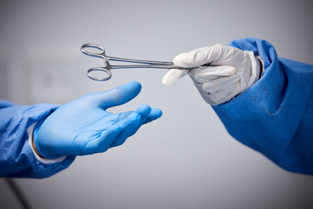 Surgery, hands or doctors with scissors with medicine or surgical procedure or healthcare in hospital. People, medical safety tools or closeup of surgeon in gloves helping in operating room in clinicの写真素材
