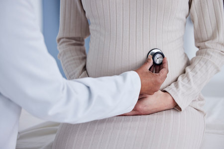 Pregnant, woman and hands of doctor in exam for pregnancy checkup, tummy or patient at the hospital....