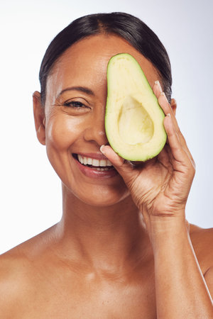 Face, skincare and senior woman with avocado in studio isolated on a white background. Happy,...