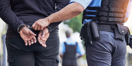 Handcuffs, crime and police with man criminal outdoors for arrested, corruption and justice. Illegal, arrest and Law enforcement with suspect for money laundering, violence or fraud, robbery or jailの写真素材
