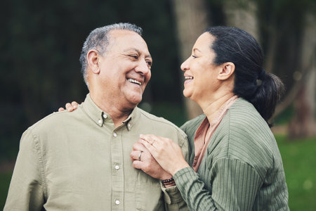 Love, talk and mature couple in nature in an outdoor park with care, happiness and romance. Happy, smile and senior man and woman in retirement embracing and bonding together in a green garden.の写真素材