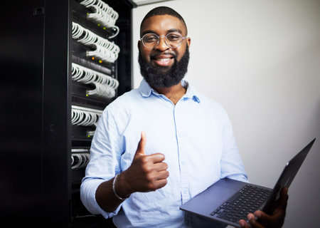 Server room, laptop and thumbs up with technician man for internet connection and software programming. Engineer black person with technology and thank you for cybersecurity system in data centerの写真素材