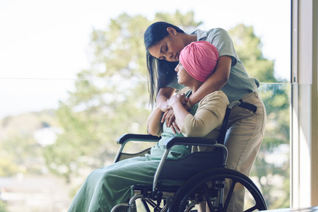 Senior mother, woman and hug with wheelchair, love and care with bonding, kindness and nursing home. Girl, embrace and elderly person with disability for support, empathy or trust by window at clinicの写真素材
