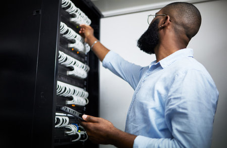 Server room, tablet and technician man with cable for internet connection for software programming. Engineer black person with tech for cybersecurity, hardware wire or maintenance in data centerの写真素材