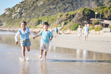 Kids, brother and sister running at beach, excited and holding hands with smile, adventure and vacation. Young children, happy and playful with race, games and freedom by ocean for summer in Hawaiiの写真素材