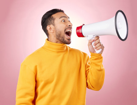 Man, megaphone and voice for news, broadcast or student sale with wow announcement on studio pink background. Young person or gen z noise with call to action, university attention or college speakerの写真素材