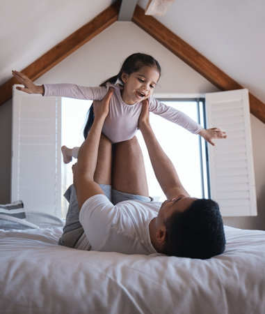 Airplane, game and child with father on a bed happy, playing and bonding in the morning together. Flying, fun and excited girl with parent in a bedroom for creative, fantasy and childhood happinessの写真素材