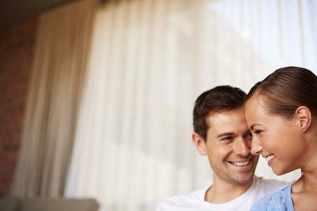Who needs anyone else. Shot of a happy young couple sitting together inside.の写真素材