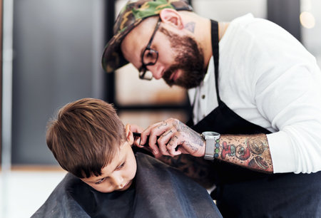 Just tilt your head a little. Cropped shot an adorable little boy getting a haircut at the barbershop.の写真素材