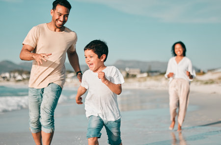Family, father and son running on beach with mother, ocean and energy with bonding on holiday, happiness and freedom. Parents, boy and carefree on tropical vacation in Mexico, love and care outdoorの写真素材