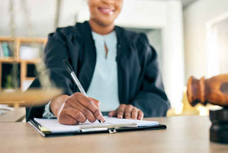 Legal, scale and hands of black woman lawyer writing for an investigation document or criminal case in law firm. Court, administration and judge working on justice or planning in attorney officeの写真素材